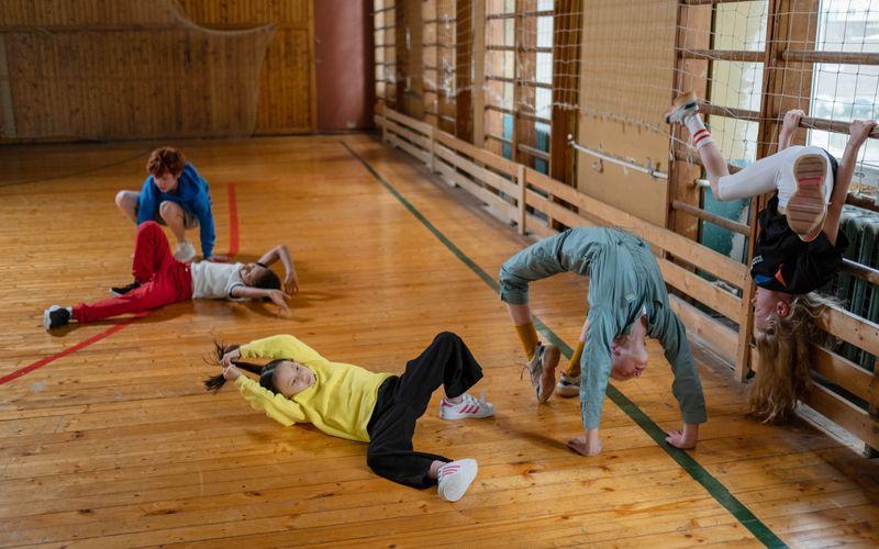 children playing active games inside a school sports hall during PE